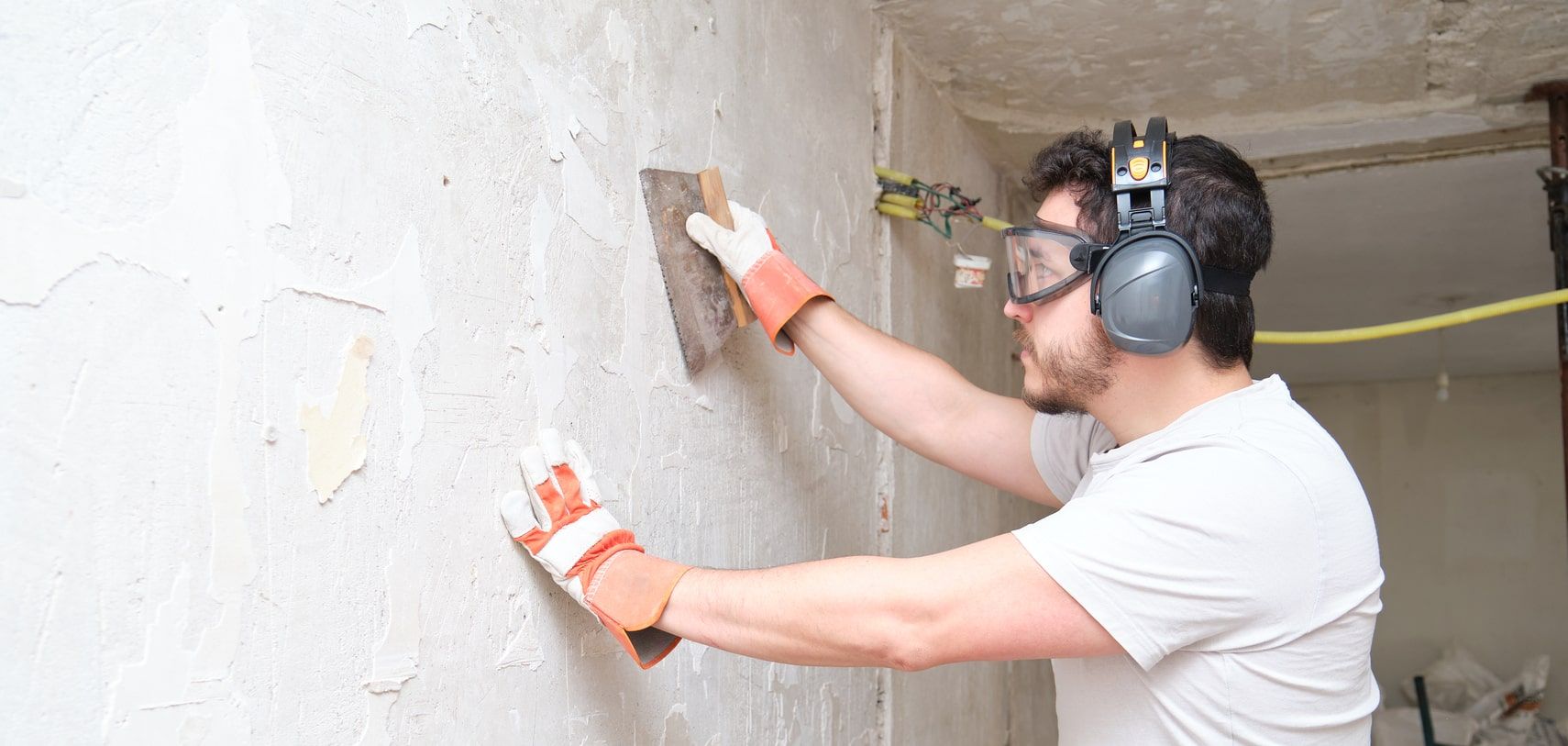 Handwerker trägt mit der Kelle Putz auf eine Innenwand auf